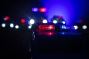 Dark, blurry image of the outline of police cars with red and blue lights on top