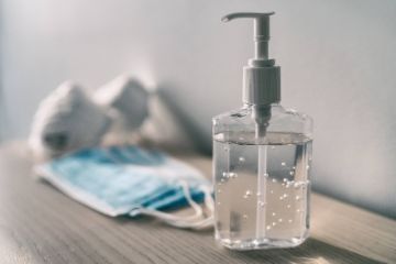 Hand sanitizer sitting next to a pile of masks