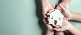 Hands holding wooden house