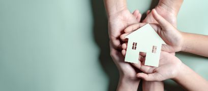 Hands holding wooden house