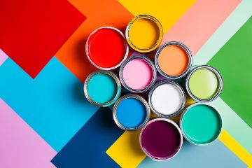 Ariel view of different sized buckets of different colored paints sitting on a colorful geometric pattern