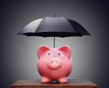 Pink piggy bank underneath a black umbrella