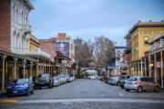 Picture of Old Sacramento, from left to right: multi-story old buildings, vehicles parked along the buildings, open street, vehicles parked along buildings, multi-story old buildings