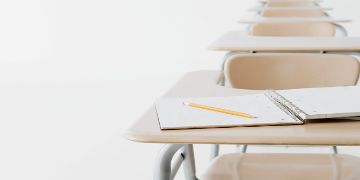 Row of student desks with notebook and pencil on top