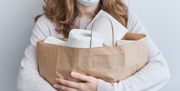 Woman holding multiple rolls of toilet paper