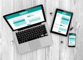 Teal and white online survey form on laptop, tablet, and phone on a light grey wooden desk