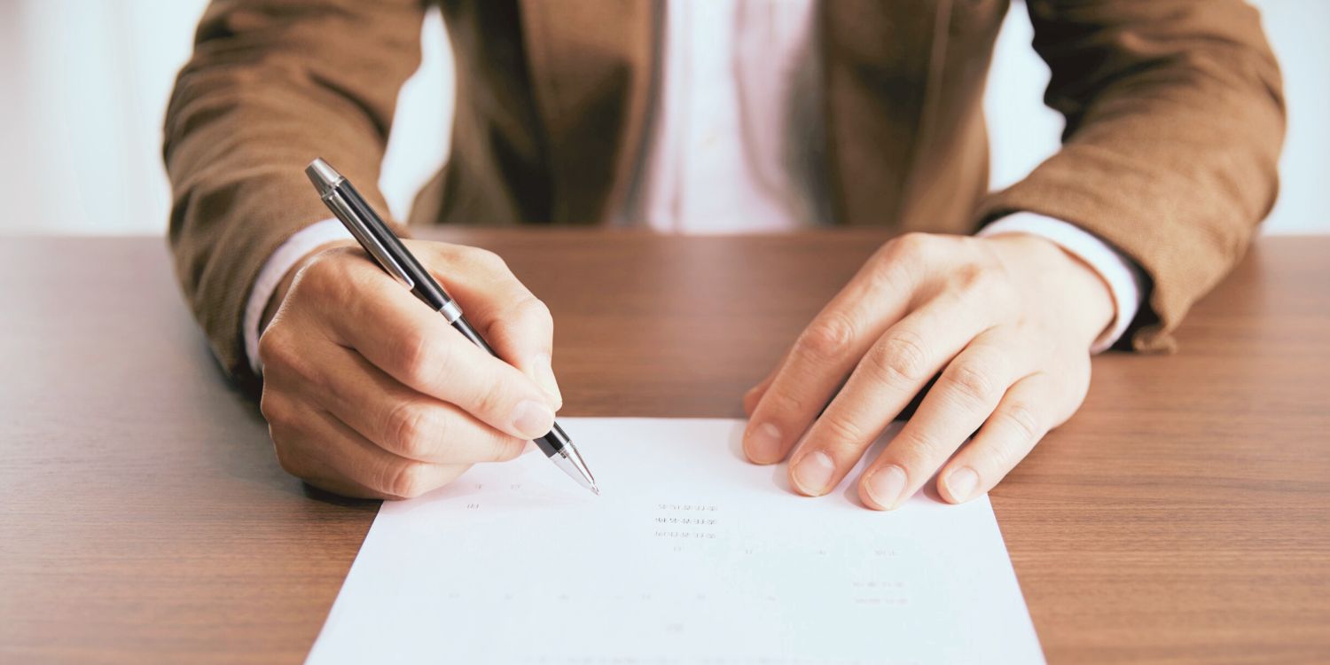Person signing a document on a table