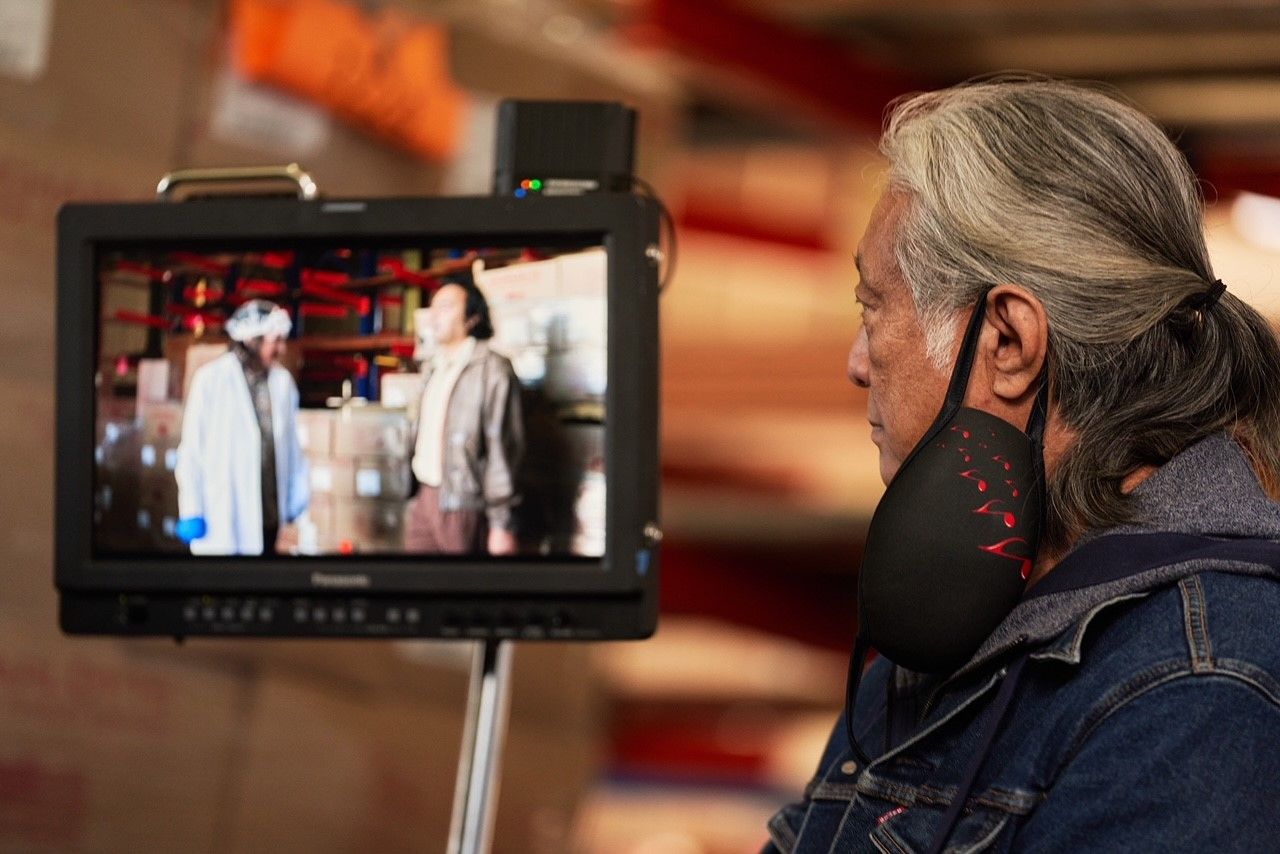 Image of a man looking at a camera image of filming taking place