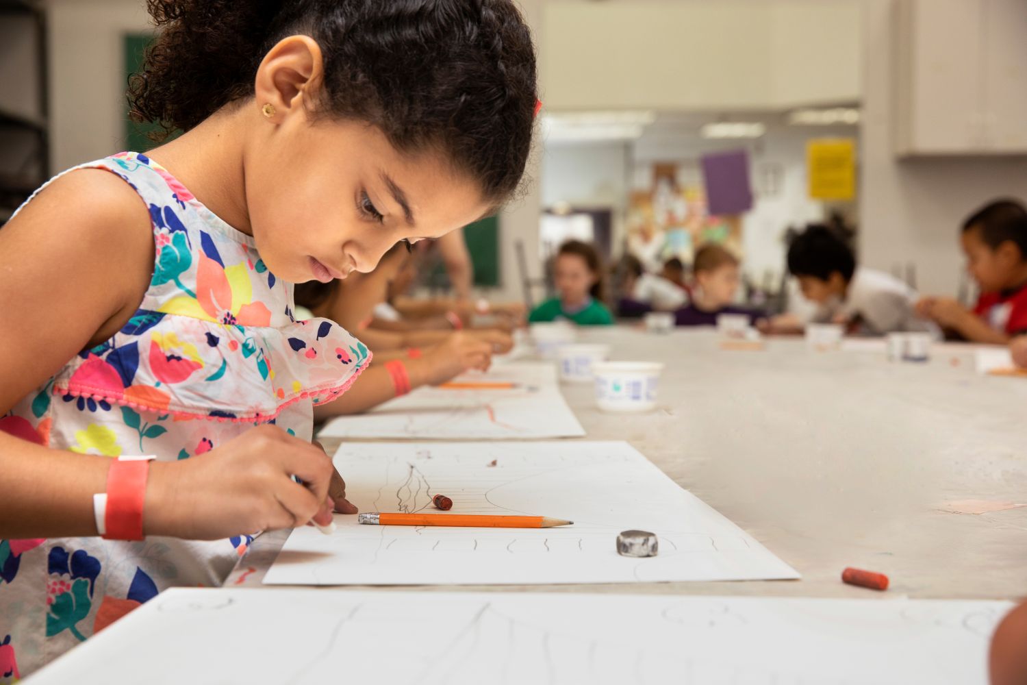 Child in classroom drawing on paper. 