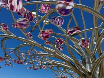 Bright pink glass leaves on a metal tree.