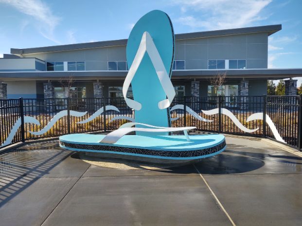 Giant flip-flops sit surreally on a moist poolside, this is the sculpture entitled Between the Toes by Artist Terrence Martin