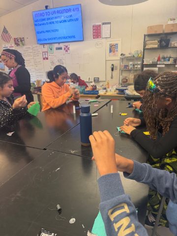 Students work at a table on a sewing project