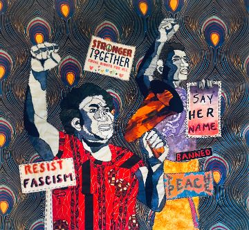 Image of a quilt depicting a protest scene. The arms, faces, and raised fists of the African American male figures are made of grey, black and blue fabrics. Red fabric makes one man's shirt., another man wears a violet shirt and yellow pants, and there is a flash of an orange bullhorn held by the man in front. There are protest signs that read, "Stronger Together", "Say Her Name", "TEACH PEACE", and "RESIST FASCISM." A repeated peacock patterned cloth in the background looks like vigil candles.