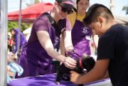 photo of front street shelter staff with a purple apron examining a black puppy with a young boy holding the puppy