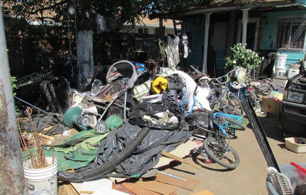photo of junk, debris and garbage in front of a home.
