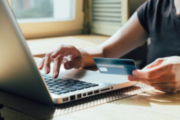 laptop with a person typing and holing a credit card