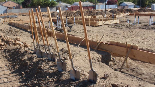 Line of shovels standing upright in the foreground of a construction site
