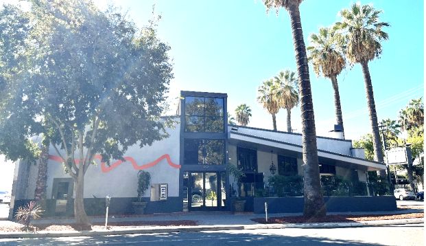 Faces gay bar, a large building with slanting roofing and enclosed patio seating. 