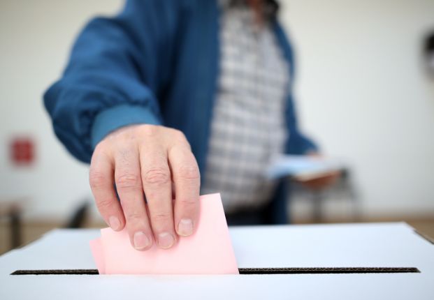 Hand putting a ballot in a ballot box