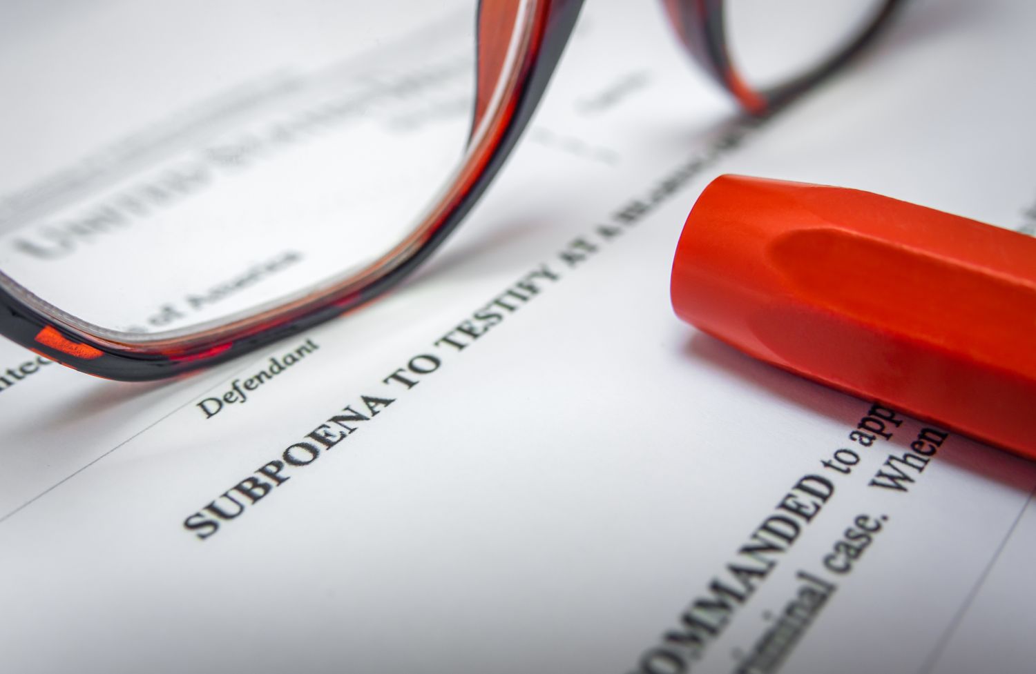 First page of a subpoena, with glasses, and red marker.