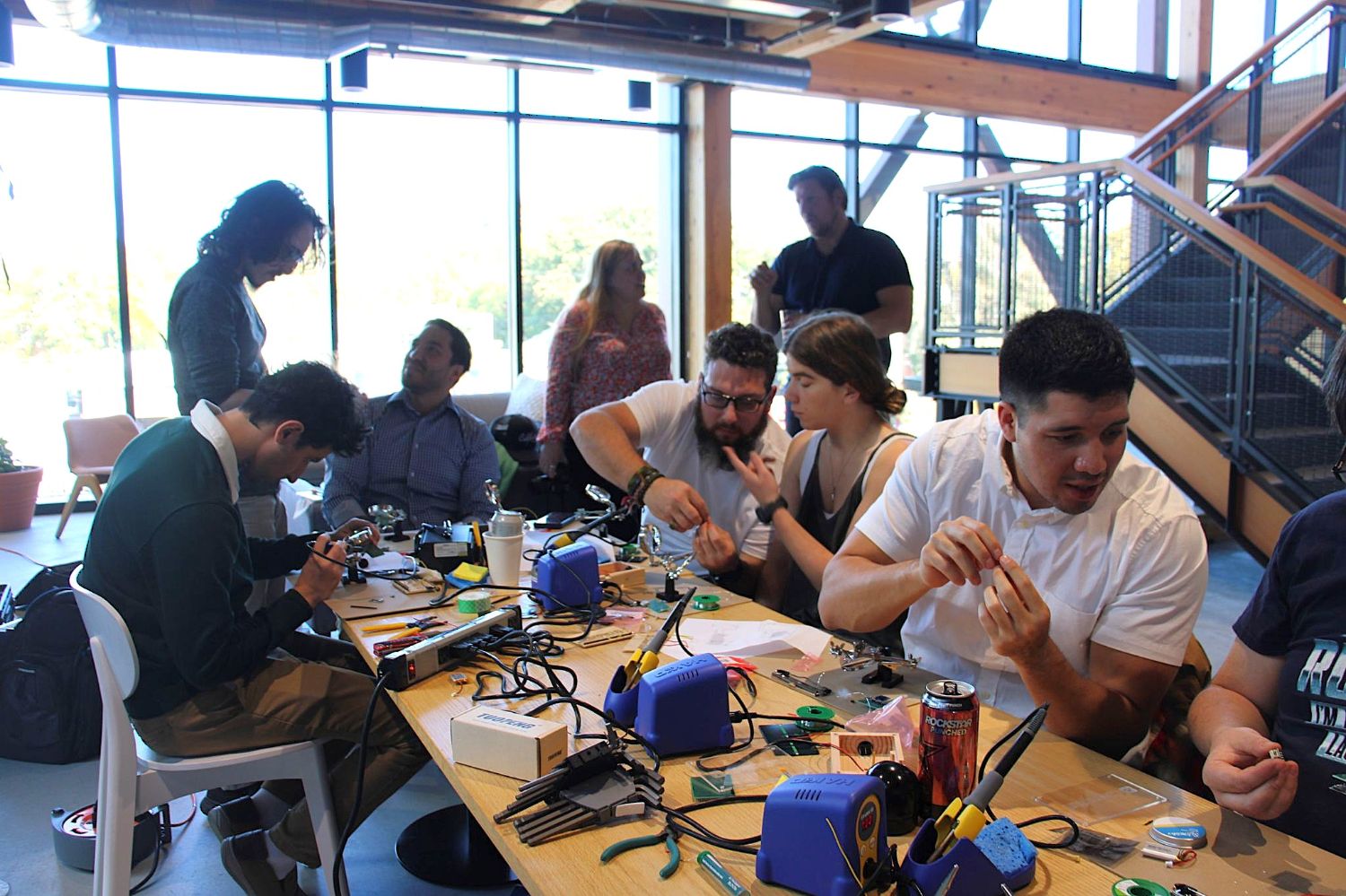 People working with electrical components at a crowded table.