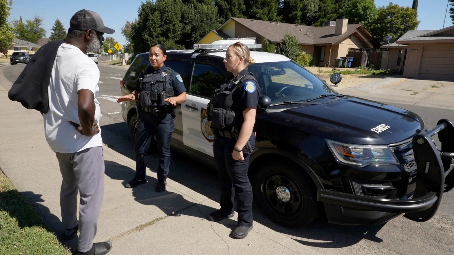 Two police officers talking to a person on the sidewalk