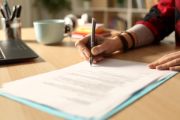 Image of hand holding a pen and signing a document