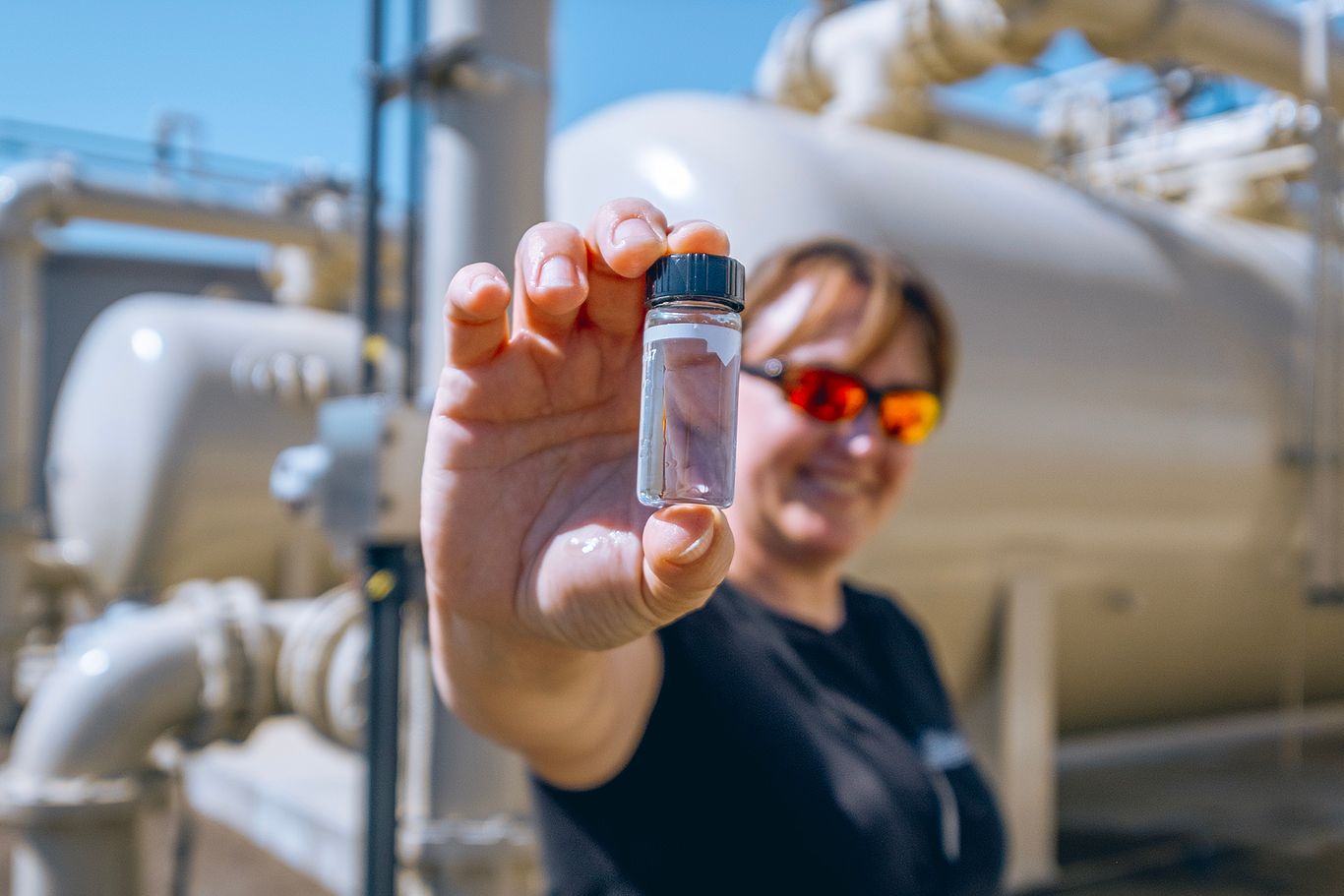 Utility worker holding a water sample up to the camera