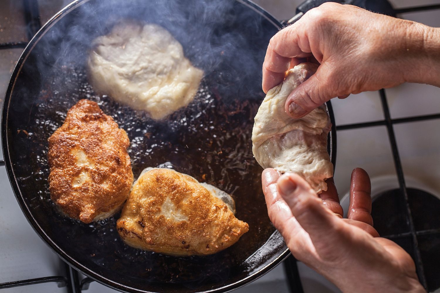 Person cooking chicken on a pan