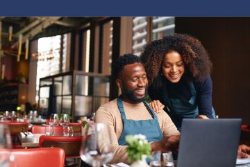 Photo of two business owners looking at a laptop