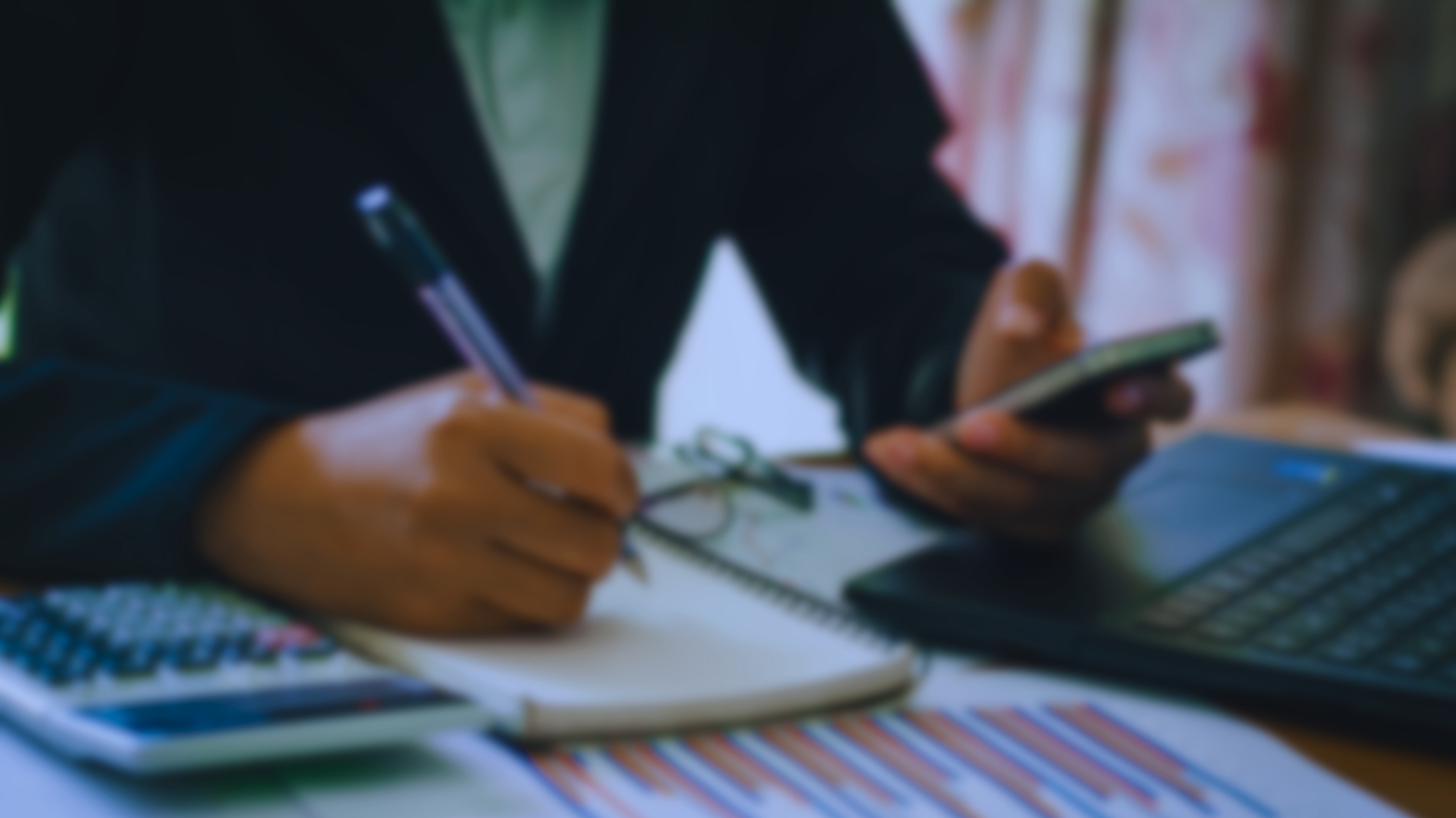 Image of person taking notes and looking at their smartphone