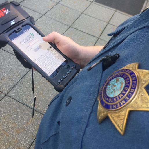 Parking enforcemen officer with parking ticket app showing on device