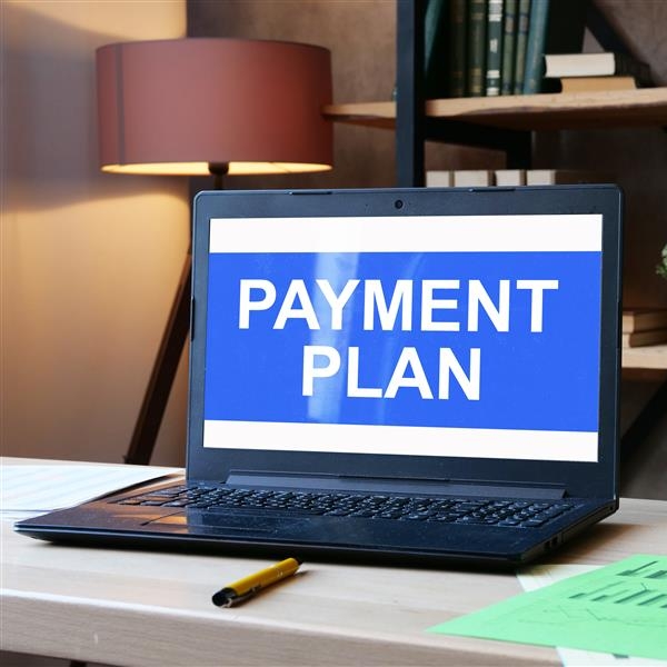 Laptop on desk with screen open and the words payment plan filling the screen