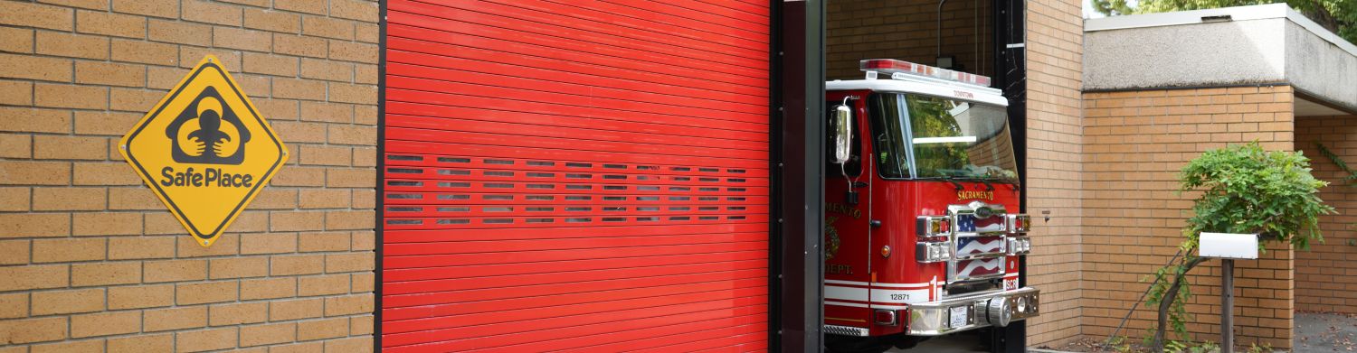 Yellow sign of the Safe Place logo on the side of a fire house