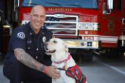 EMBER, A PEER SUPPORT K9 AND CAPTAIN ALAMO POSING IN FRONT OF A FIRE ENGINE