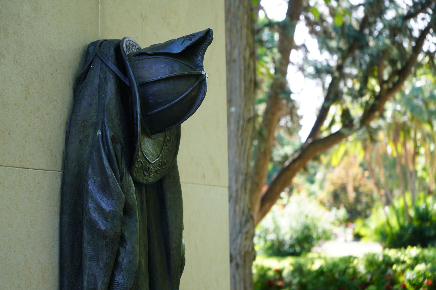 STATUE OF FIRE COAT AND HELMET WITH TREE BRANCHES IN THE BACK