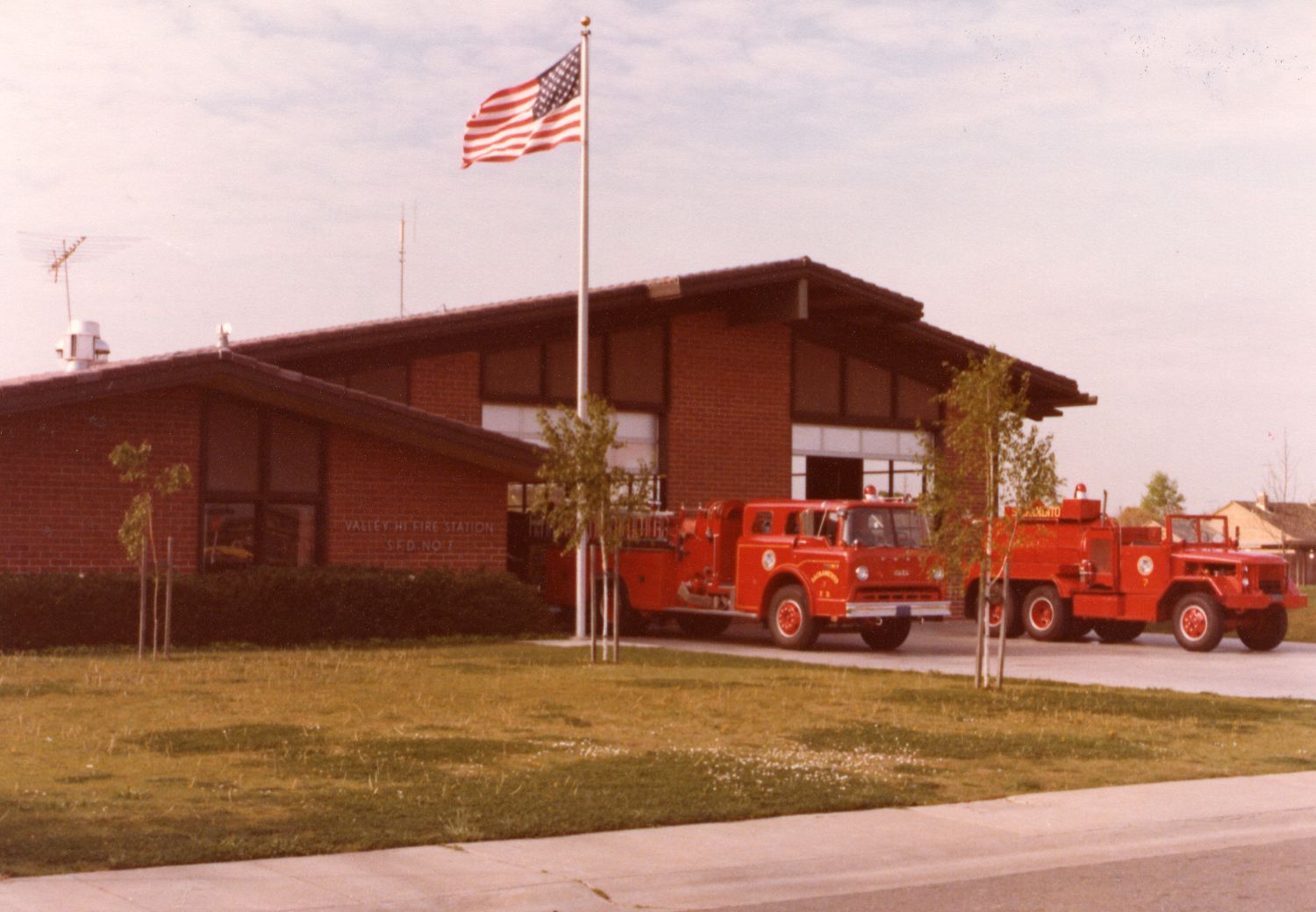 Sacramento Fire station 7 vintage photo of the front of the firehouse with engine and truck and flag flying above. 