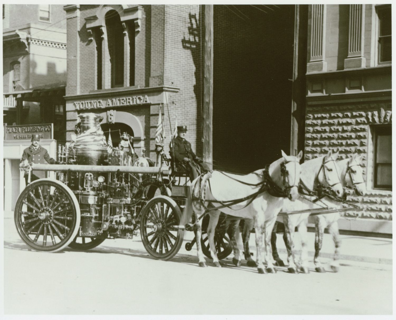 Black and white photo of firefighters traveling by horses. 