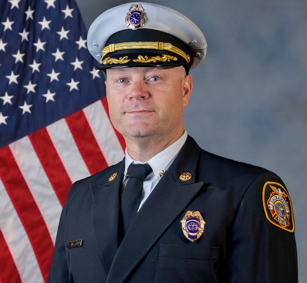 photo of assistant fire chief billiter in full uniform with flag in the background