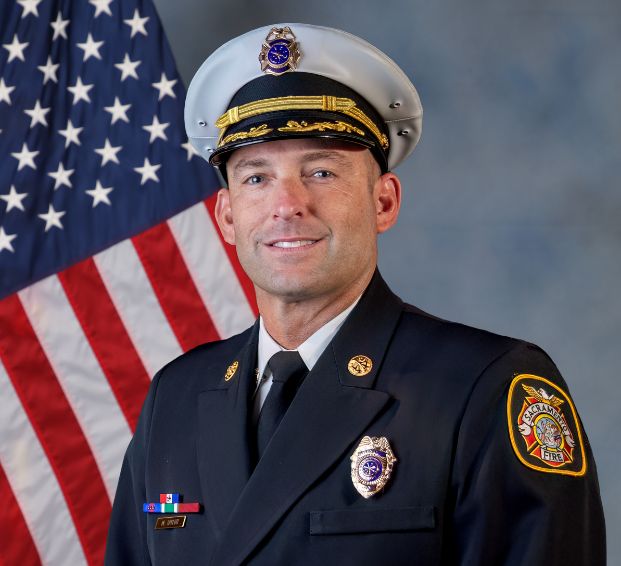 photo of assistant fire chief mike taylor in full uniform with flag in the background