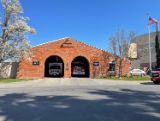 brown brick fire station with large doors open showing two fire engines