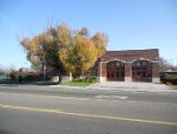 fire station made of brown and white brick. Large tree in front of fire house.