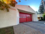 Fire station made of white walls with red garage doors. spelling out Station 6 in the front. 