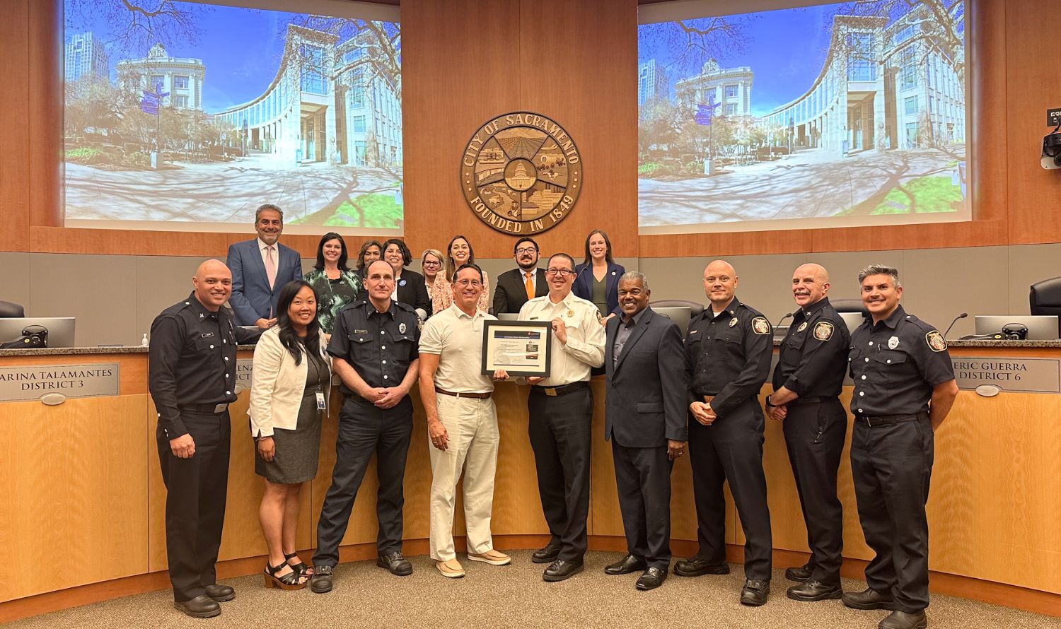 Sacramento Fire and Sacramento City council posing with a certificate inside the Council Chambers