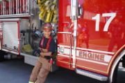 young kid sitting on the side of a red fire engine with the number 17 on it.