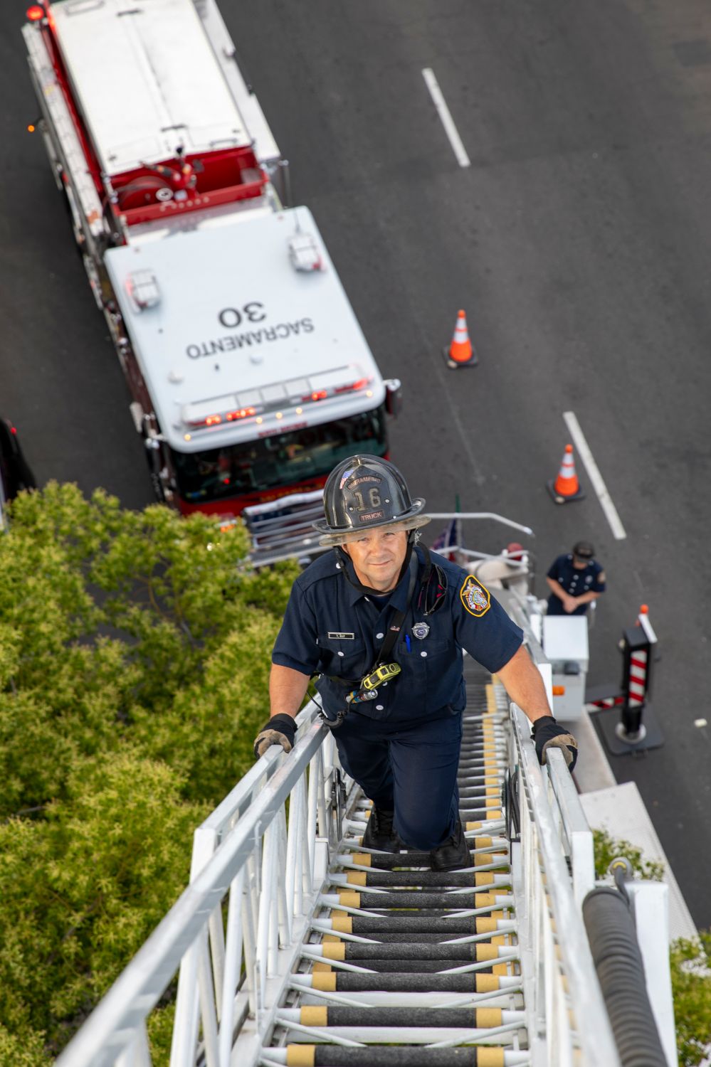 fireman climbing a fire ladder with a fire truck in the background