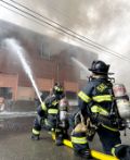 two firefighters fighting a fire on their knee with a water hose