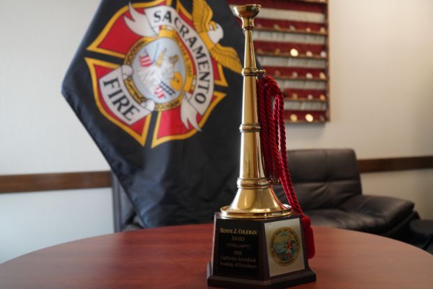 Ronny J. Coleman trophy with a Sacramento fire flag in the background