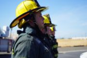 a line of firefighters in full fire fighting gear and yellow helmet.