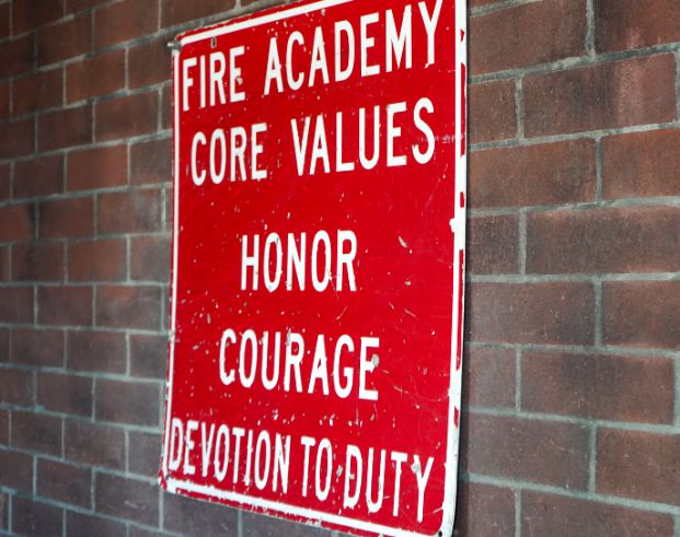 a photo of a red sign with white letters that read "Fire Academy Core Values: Honor, Courage, Devotion to Duty." 